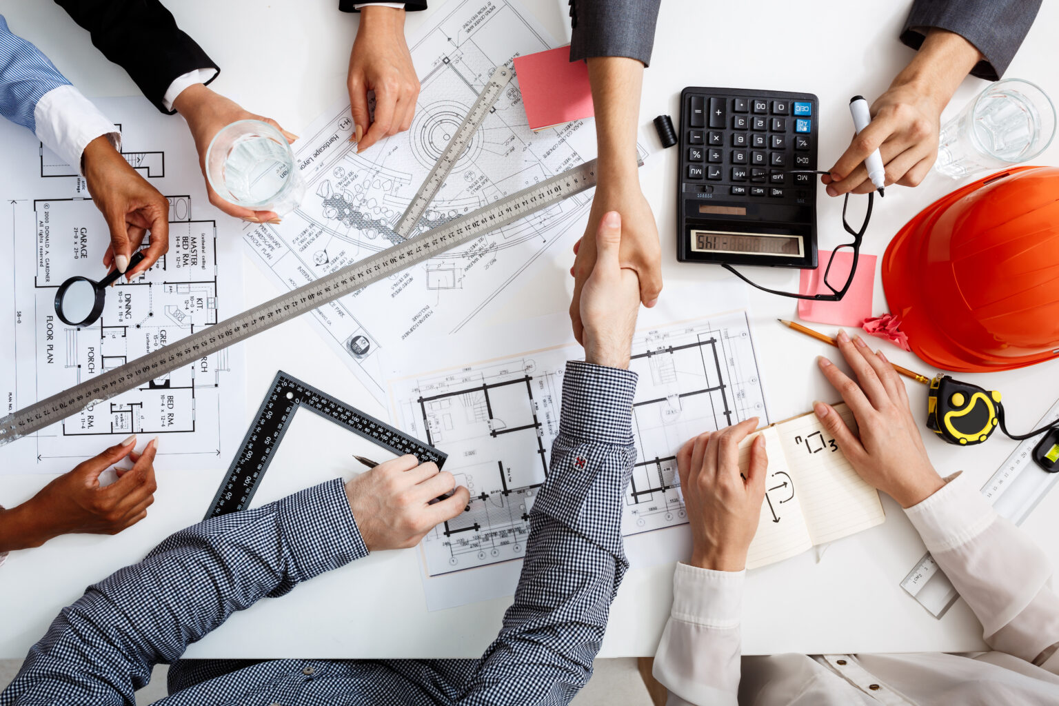 Picture of businessmen's hands on white table with documents, coffee and drafts